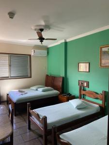 a room with three beds and a green wall at Garden Hotel in Nova Era