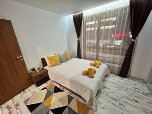 a bedroom with a bed with yellow pillows and a window at Le Bijou МОЛ Плаза in Plovdiv