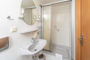 a white bathroom with a sink and a shower at Hotel Waldhaus Waltershausen in Waltershausen