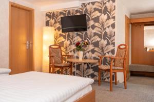 a hotel room with a bed and a table and chairs at Hotel Waldhaus Waltershausen in Waltershausen