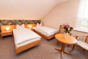 a hotel room with two beds and a table at Hotel Waldhaus Waltershausen in Waltershausen