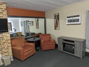 a room with a living room with a fireplace and chairs at Hickory West Inn in Hickory Hills