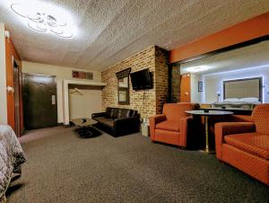 a hotel room with a bed and a couch and chairs at Hickory West Inn in Hickory Hills