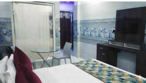 a bedroom with a bed and a table and a tv at Hotel Ravi Palace Agra in Agra