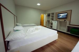 a bedroom with two white beds and a television at Ody Park Resort Hotel in Iguaraçu