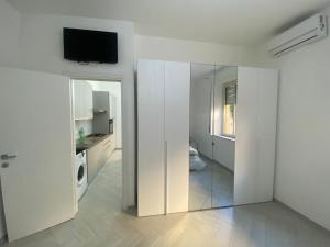 a white kitchen with a sliding glass door with a television at OLYMPO HOUSE senza balcone in Agrigento
