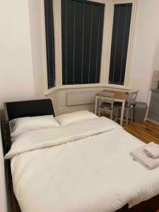 a bedroom with a large white bed and a table at Self Contained Studio Flat Acton Central West London in London