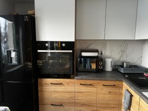 a kitchen with a black refrigerator and wooden cabinets at Apartament z widokiem 3 in Chełm
