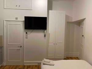 a bedroom with a bed and a flat screen tv at Self Contained Studio Flat Acton Central West London in London