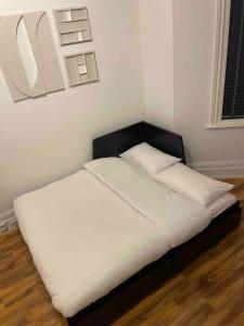 a bed with white sheets and a black head board at Self Contained Studio Flat Acton Central West London in London