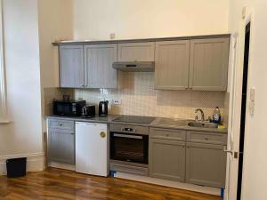 a kitchen with gray cabinets and a white refrigerator at Self Contained Studio Flat Acton Central West London in London
