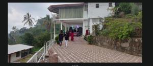 a group of people walking down a walkway towards a building at Agape center in Haputale
