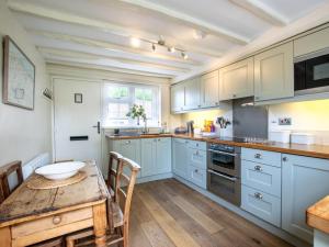a kitchen with blue cabinets and a wooden table at 2 Bed in Kelling Holt oc-76755 in Kelling
