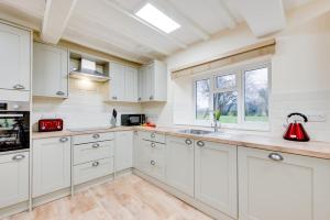 a kitchen with white cabinets and a red kettle on the counter at 3 Bed in Machynlleth oc-bow306 in Darowen