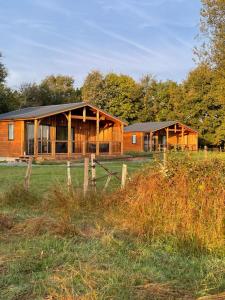 a wooden house in a field with a fence at Les cottages du Tremble in Ruffec