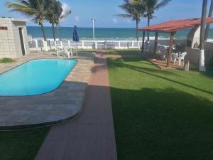 a swimming pool with the ocean in the background at Pousada Tropical dos Corais in Cabo de Santo Agostinho