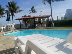 a swimming pool with chairs and a gazebo at Pousada Tropical dos Corais in Cabo de Santo Agostinho