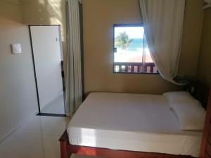 a small bedroom with a bed and a window at Pousada Tropical dos Corais in Cabo de Santo Agostinho