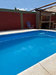 a blue swimming pool with a chair next to a brick wall at departamento familiar 2 in Malargüe