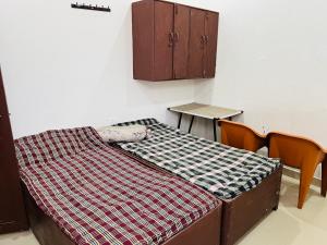 a bed in a room with two chairs and a table at BNT BOYs HOSTEL in Lucknow