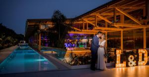 a bride and groom standing next to a pool at night at Tancat de Codorniu in Les Cases d'Alcanar +83 photos