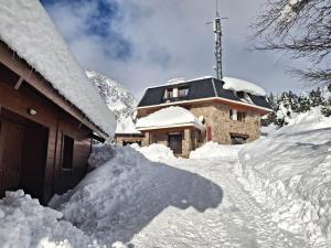 a house covered in snow next to a building at Bungalow a Setcases i Vallter in Setcases