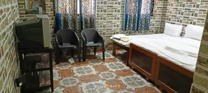 a room with a bed and two chairs and a tv at Seaway inn guesthouse in Baga