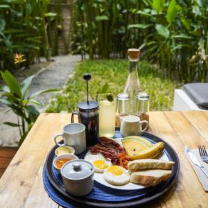 a plate of breakfast food on a wooden table at Focus Rooms in El Nido