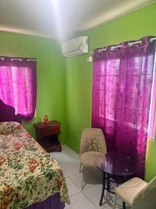 a bedroom with pink curtains and a bed and a table at Reggae Moon Guesthouse in Falmouth +18 photos
