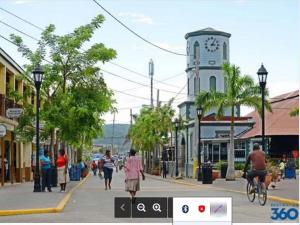people walking down a city street with a clock tower at Reggae Moon Guesthouse in Falmouth