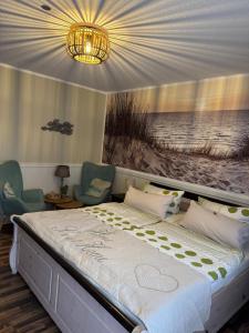 a bedroom with a bed and two chairs and a chandelier at Pension Mien Fründt in Baabe