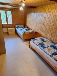 two beds in a room with wooden walls at Rustikale Wohnung auf dem Bauernhof in Malters