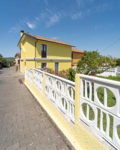 a yellow house with a white fence at Pantaleo Rooms in Santadi