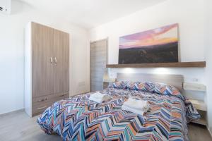 a bedroom with a colorful bed and a painting on the wall at Pantaleo Rooms in Santadi