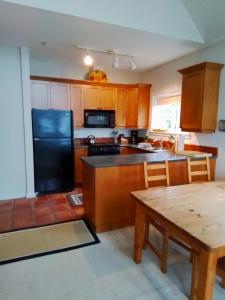 a kitchen with a black refrigerator and a table at 203 at Water's Edge in Ucluelet +25 photos