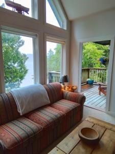 a living room with a couch and large windows at 203 at Water's Edge in Ucluelet
