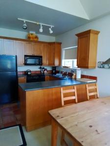 a kitchen with wooden cabinets and a black refrigerator at 203 at Water's Edge in Ucluelet