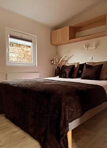 a bedroom with a large bed with pillows and a window at Chalet de Hofstee 118 in Nunspeet