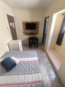 a room with two beds and a table with a television at Rioli quarto 2 in Caruaru