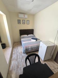 a small room with two beds and a refrigerator at Rioli quarto 2 in Caruaru