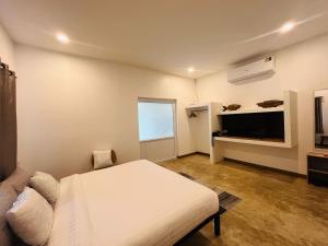 a bedroom with a white bed and a television at Modern Elephant Lagoon Villa in Ko Chang