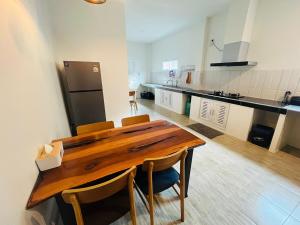 a kitchen with a wooden table with chairs and a refrigerator at Modern Elephant Lagoon Villa in Ko Chang