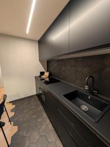 a kitchen with black cabinets and a sink at Ferienwohnung Flumserberg, Liftnähe & Gratis Parkplatz in Flumserberg