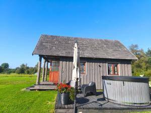 a small house with an umbrella and flowers in front of it at Brīvdienu mājas Lejnieki in Strante