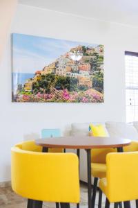 a table with yellow chairs and a painting of positano at Cozy 2BR - Beach & Trail - Bikes, Fire Pit in St. Petersburg