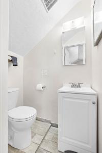 a white bathroom with a toilet and a sink at Cozy 2BR - Beach & Trail - Bikes, Fire Pit in St. Petersburg +30 photos