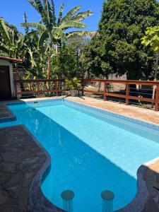 a blue swimming pool with a wooden fence and trees at Keller Reservas in Resende