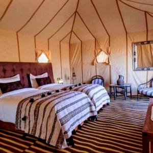 a bedroom with two beds in a tent at Magic Luxury Camp in Merzouga