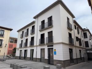 a white building with black windows and balconies at Urban Cube Hostel Granada in Granada