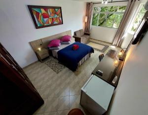 a view of a bedroom with a blue bed and pink pillows at Pousada Casa Verde - Curitiba in Curitiba